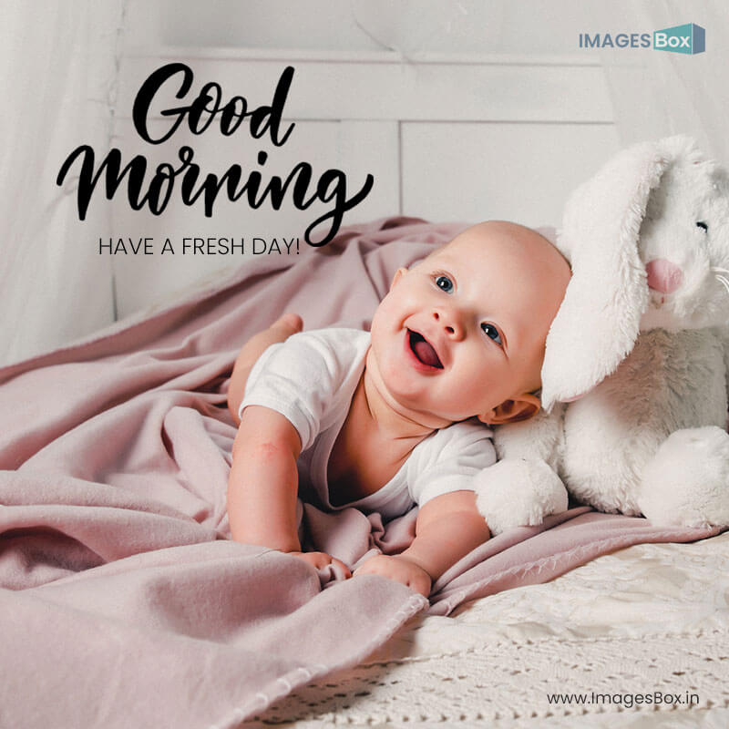 Good morning baby - little baby lays bed with toy rabbit smiles 2023